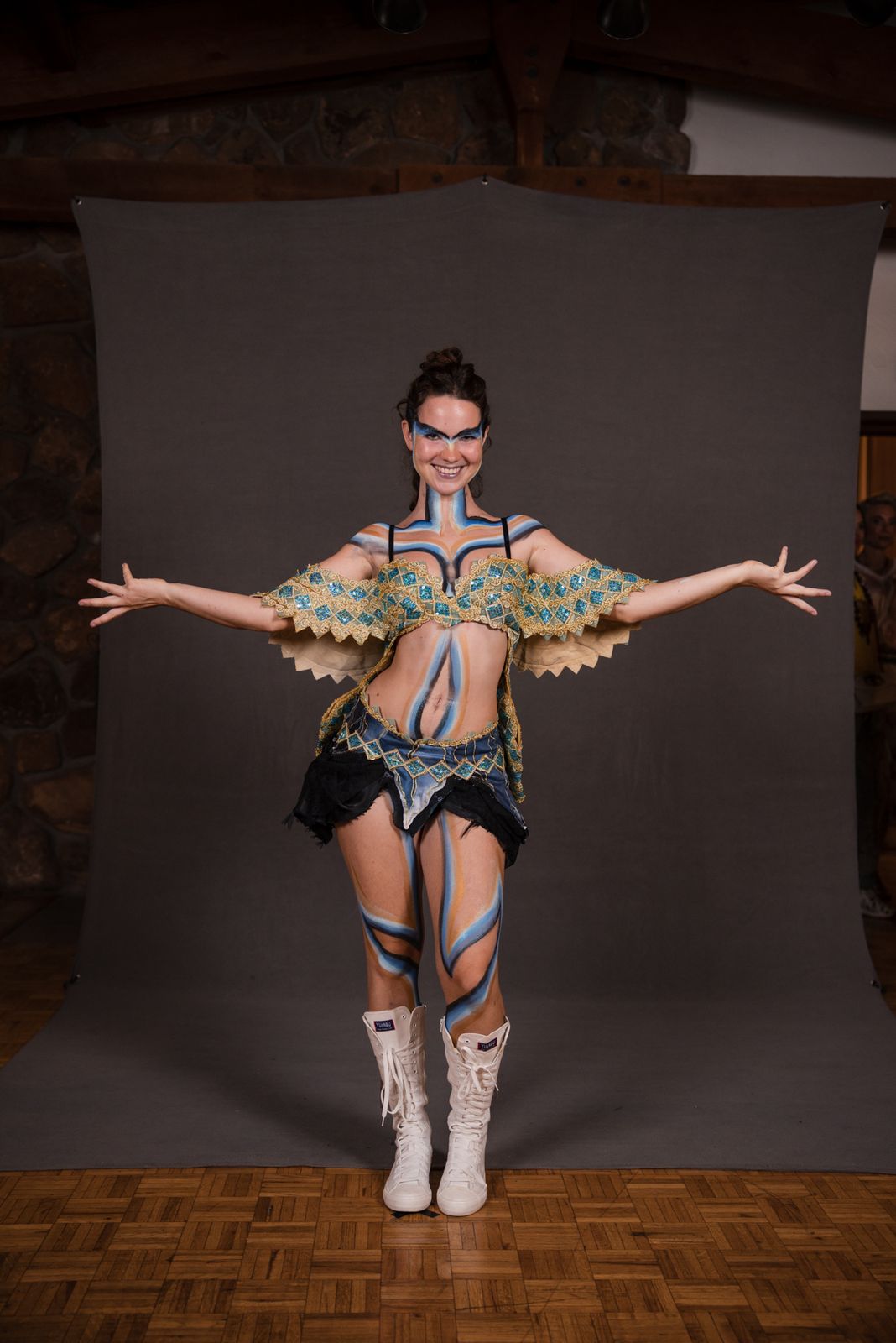 Model with arms spread in a feathered wing top