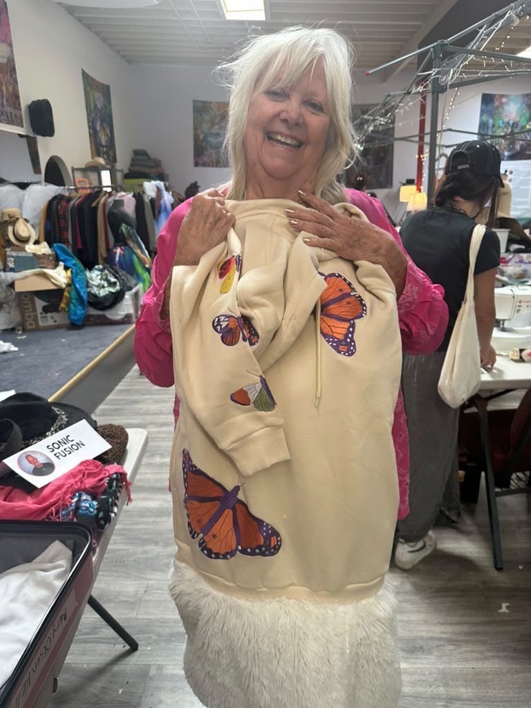 Designer holding up a sweater with monarch butterflies
