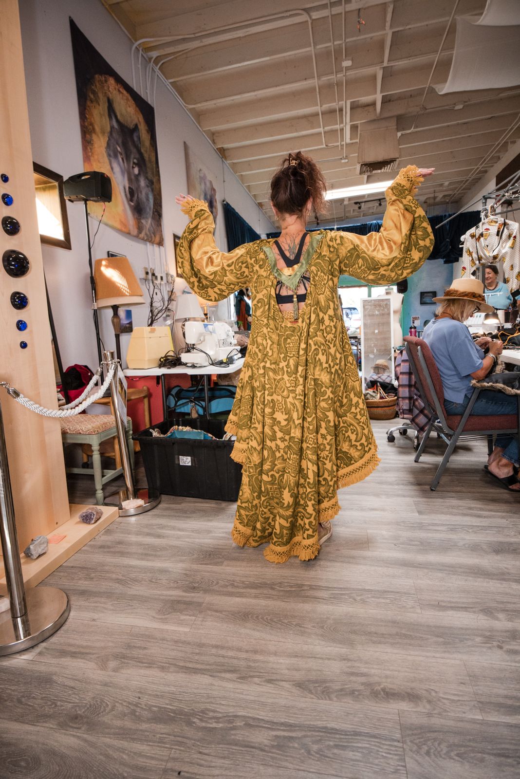 Designer trying on a gold patterned dress mid-build