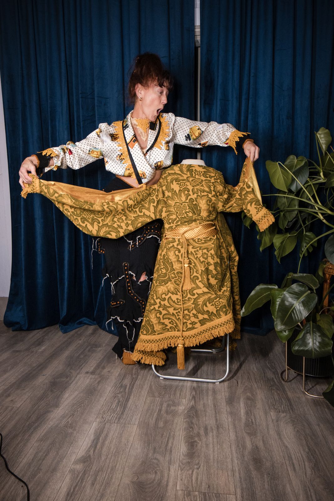 Designer holding out the sleeves of a gold gown